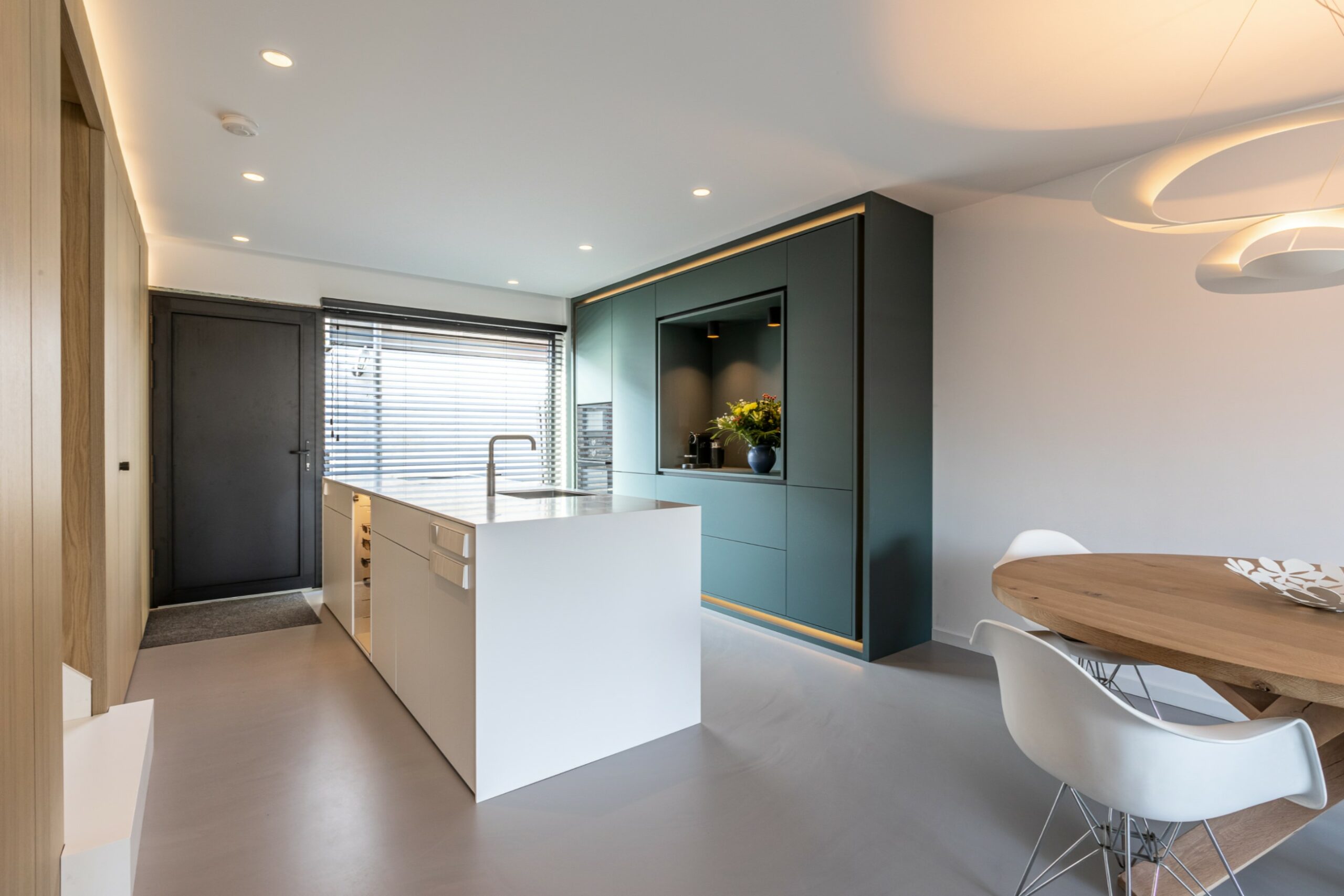 Moderne op maat keuken met wit kookeiland en donkergroene niswandkast voor een luxe en functionele indeling