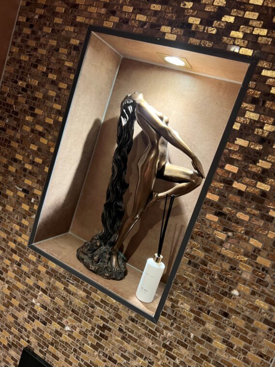 Luxe toilet met mozaïektegels, ingebouwde nis met kunstzinnige sculptuur en sfeervolle verlichting.