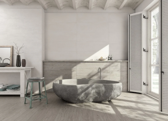 Badkamer met Grespania cementlook en houtlook tegels, natuurstenen bad en daglicht voor een serene spa-uitstraling.