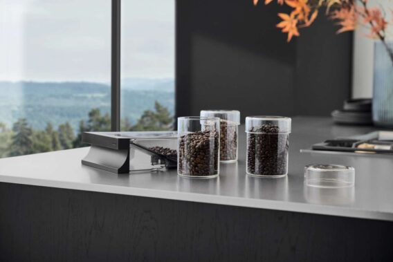 Glazen potten met koffiebonen op een keukenblad in moderne keuken met Gaggenau apparatuur.